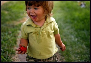 Kids should garden because it gives them exercise, as this little boy with the tomato shows.