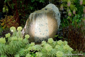 fountain made of a giant rock, surrounded by flowers