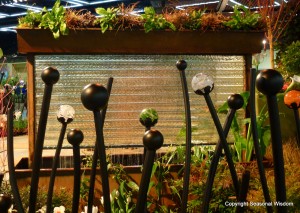 fountain made of iron and glass with planter on top