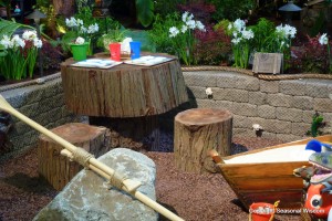 close-up of kids garden with wooden table, teeter totter and sandbox.