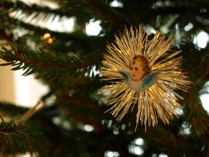 Happy holidays with an angel ornament on a christmas tree
